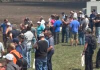 A crowd gathers at a liquid manure pit, with machinery nearby.