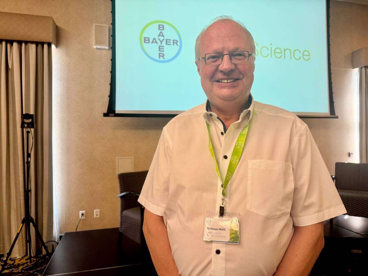 Andreas Mehl stands in front of a projection screen showing the Bayer Crop Science logo