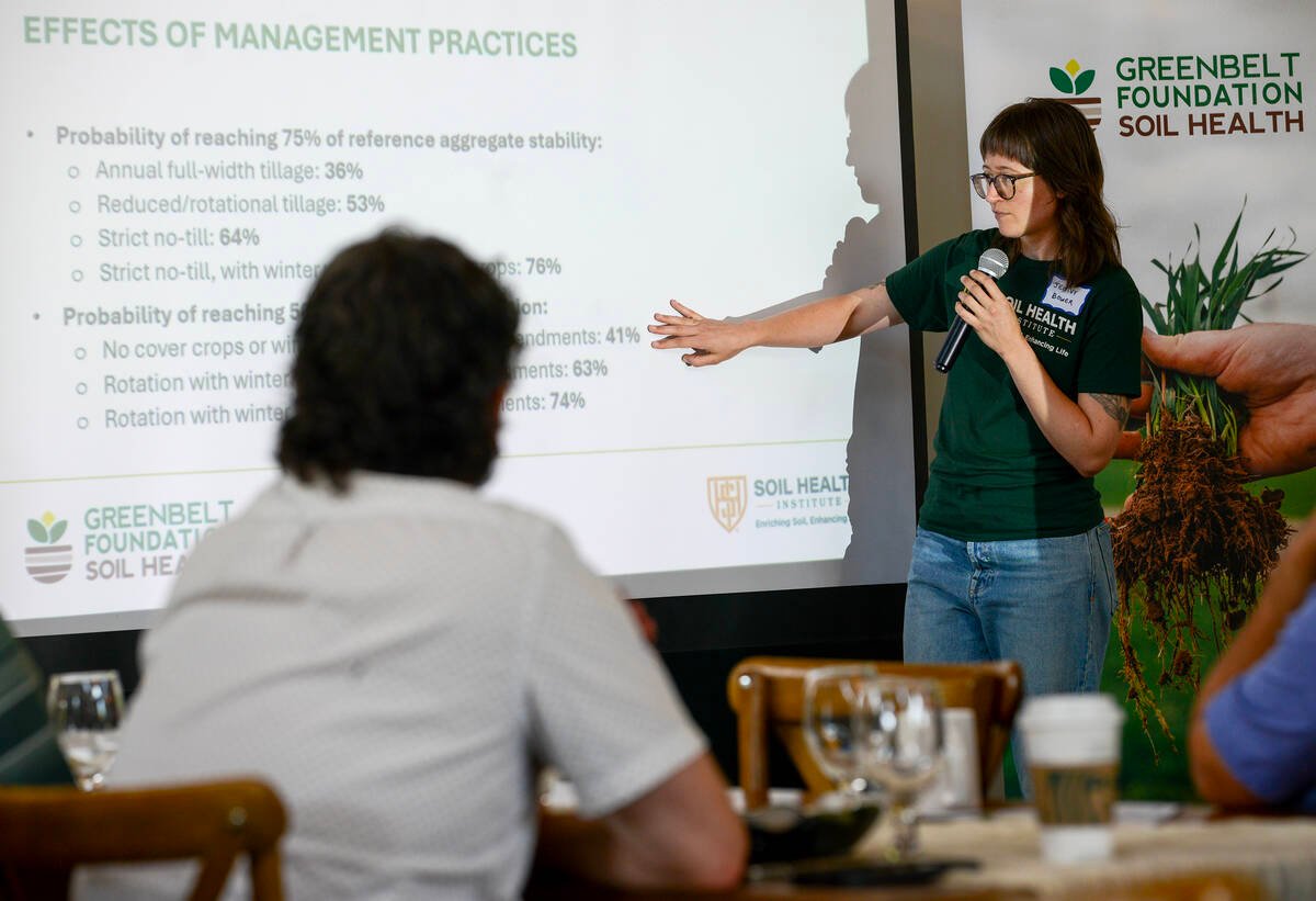 Jenny Bower reaches toward a slide titled Effects of Management Practices while holding a microphone. Photo: Diana Martin