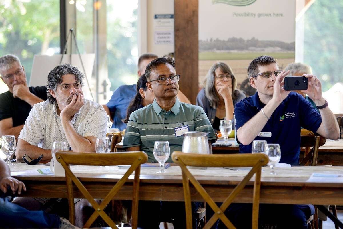 Seated attendees listen during a presentation at an indoor event space. Photo: Diana Martin