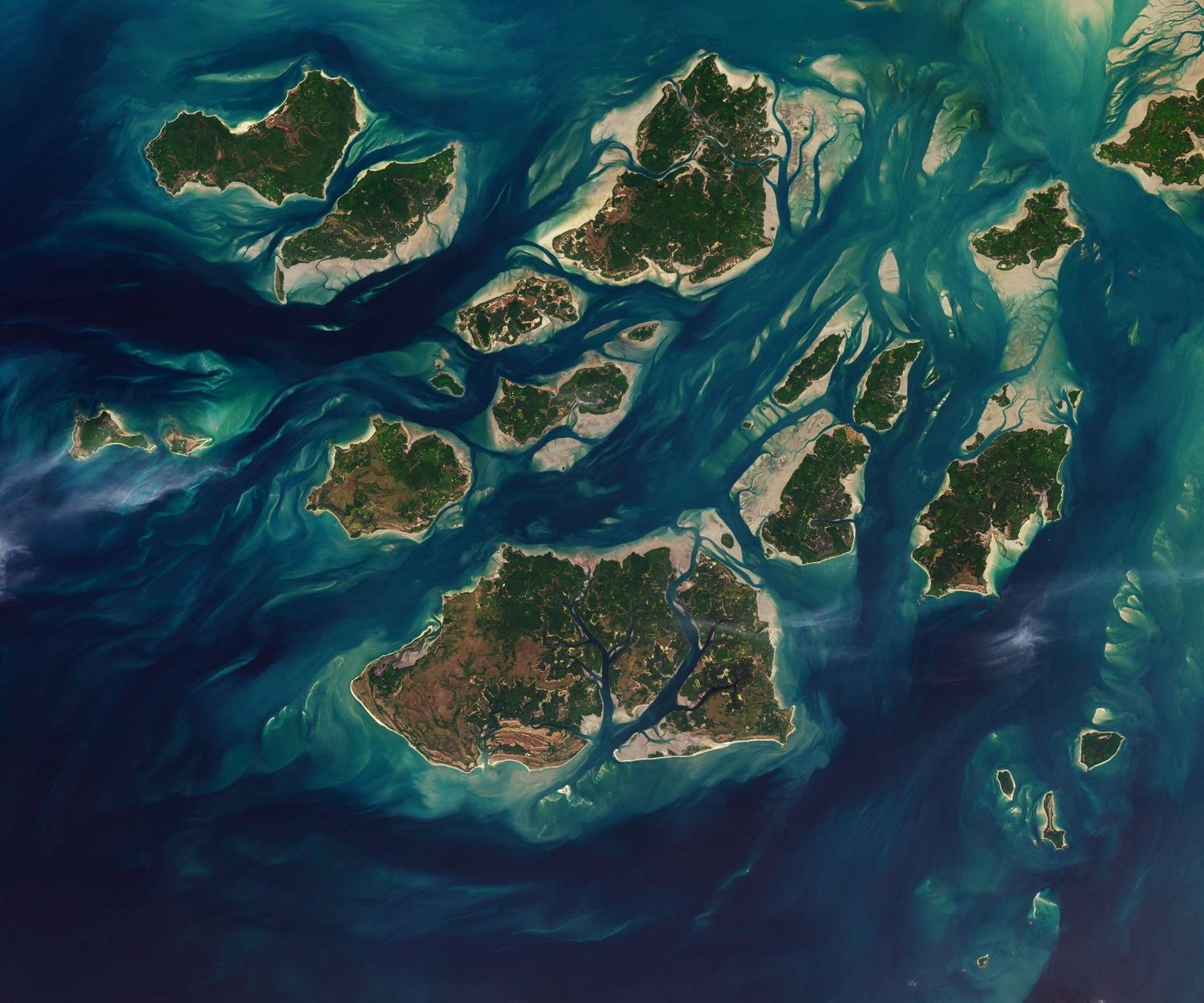 A satellite image shows a cluster of green islands surrounded by beige sand flats and networks of channels full of dark blue water.
