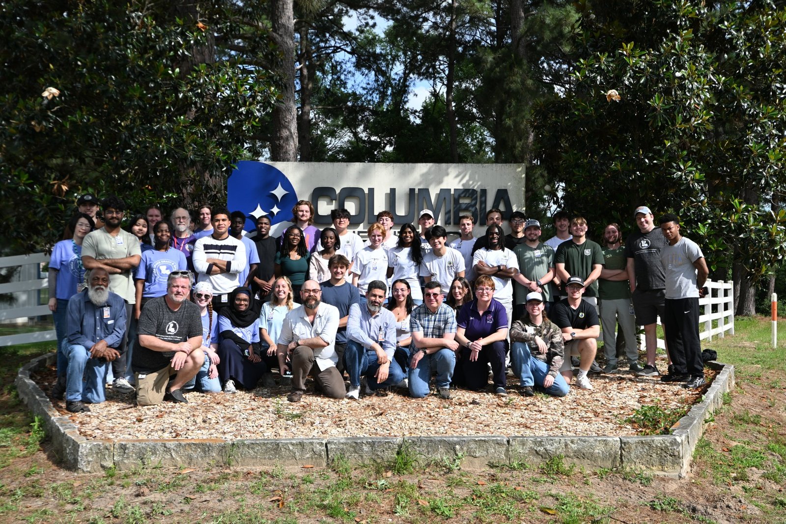 A large group photo of students and instructors from the LaACES program smiling together outdoors. They are gathered in front of the large sign for the Columbia Scientific Balloon Facility