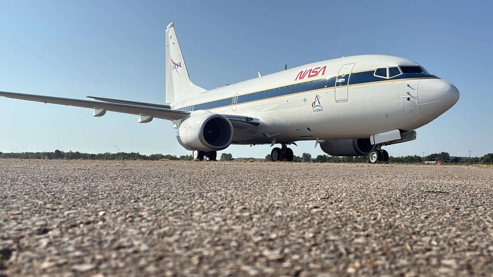 A large, white aircraft sits on a concrete surface after being painted with new NASA logos in red, white and blue.