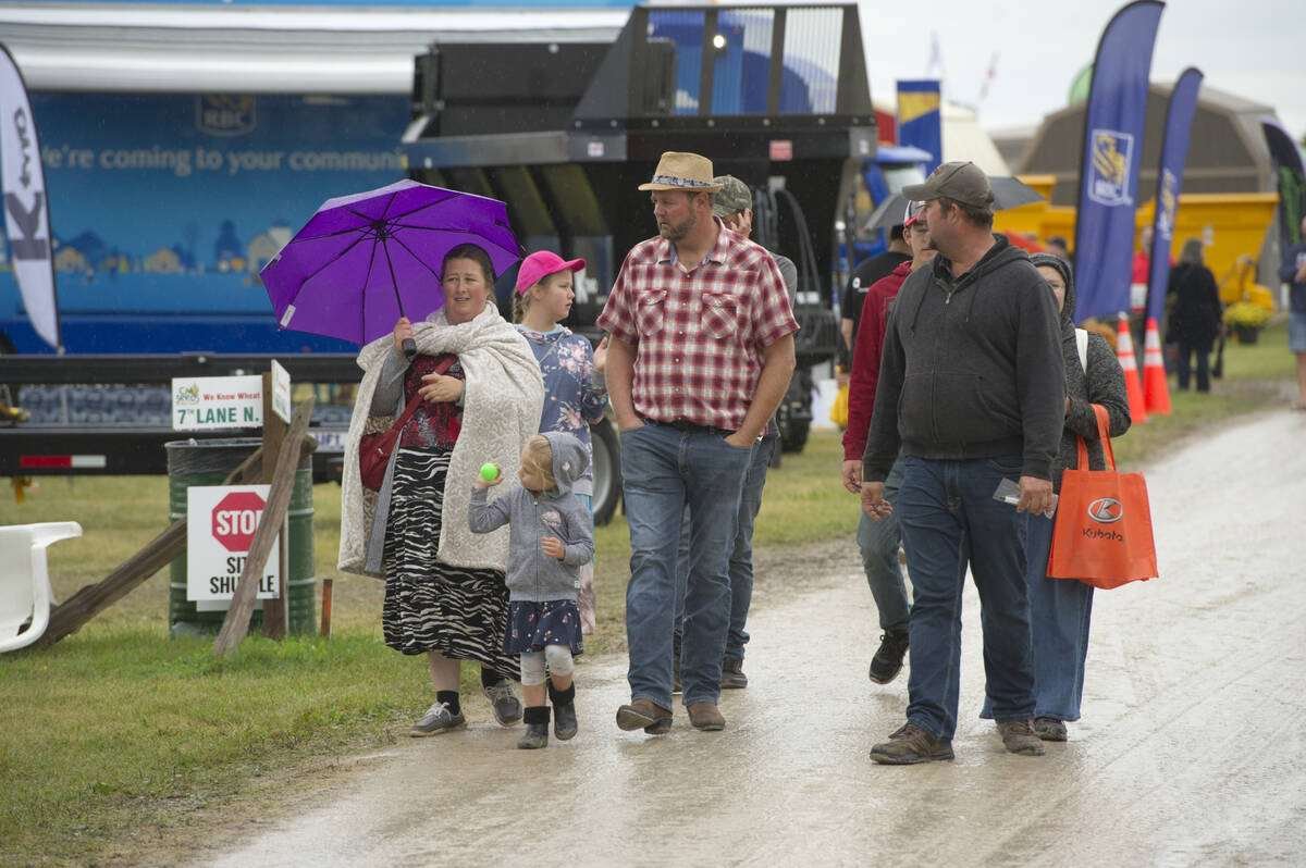Families walk on a wet gravel lane past exhibitor displays in the rain at Canada's Outdoor Farm Show. Photo: file