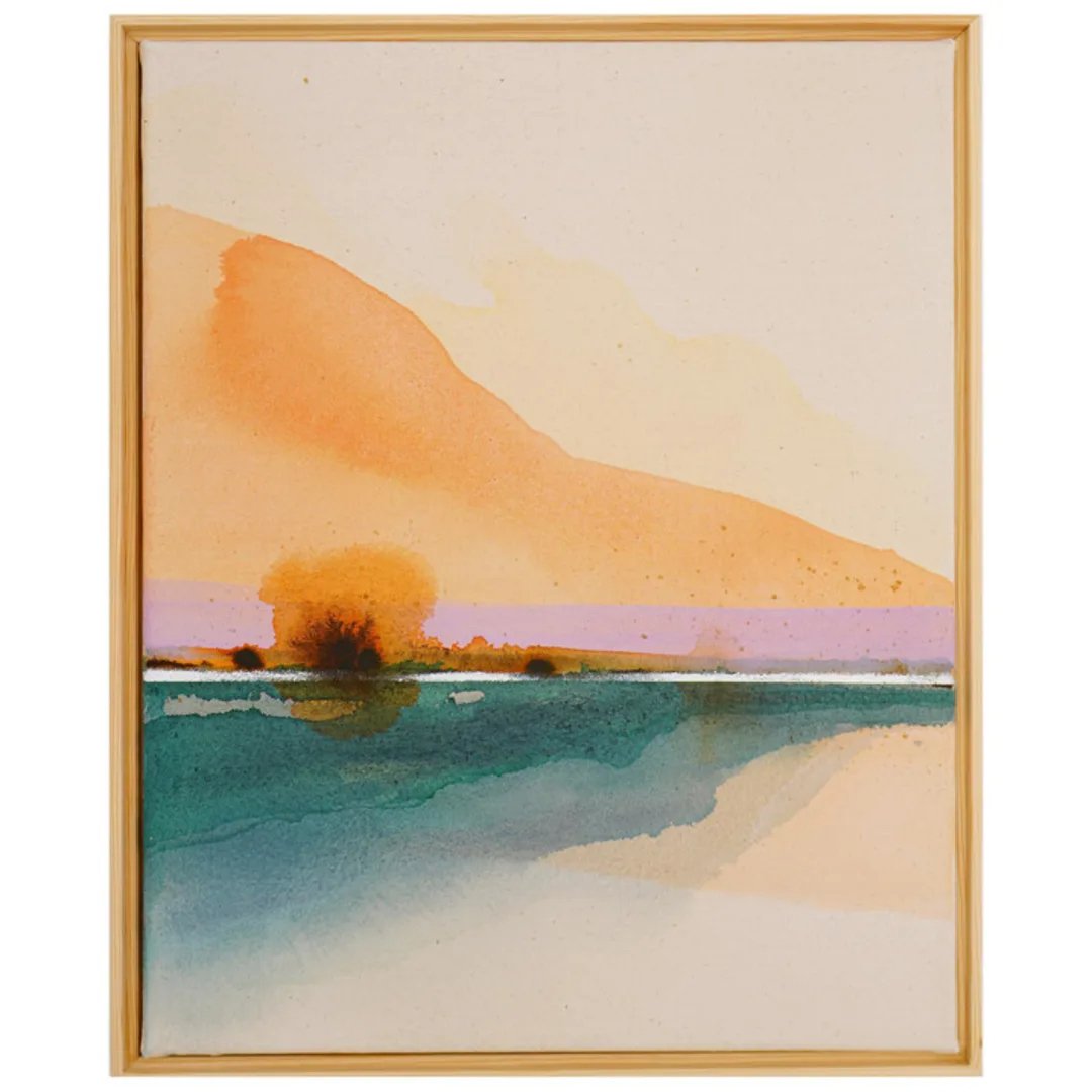 Abstract watercolor painting with warm orange and pink hues above a green and blue area, evoking a landscape with reflections, framed in light wood.