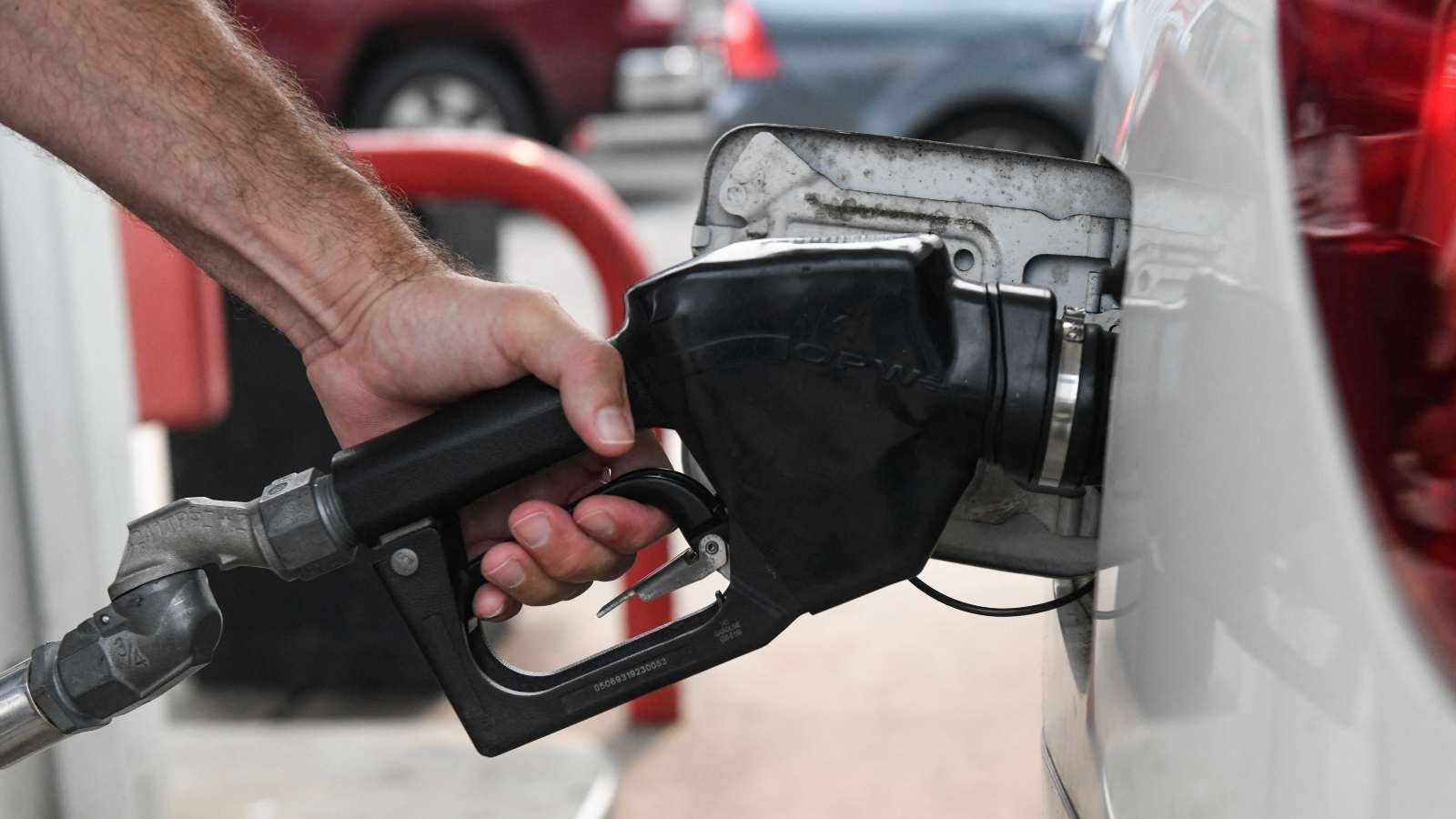 A man's hand holds a gas pump