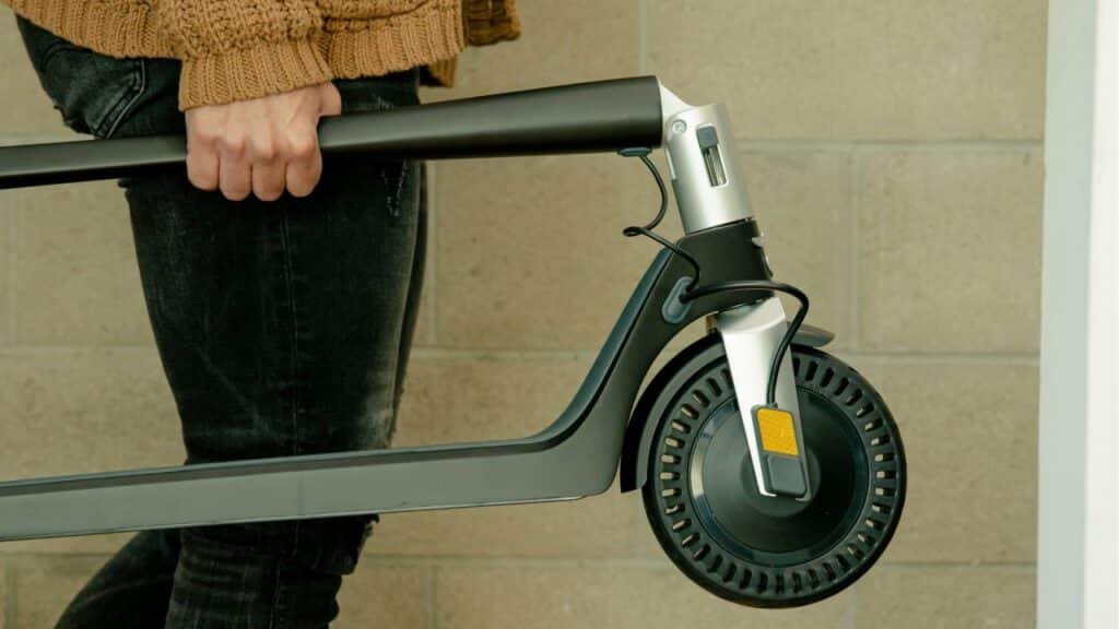 Unagi Scooters in 2026: Why the Classic and Voyager Are Still Smart Buys 1 Rider carrying a folded Unagi Model One electric scooter one-handed