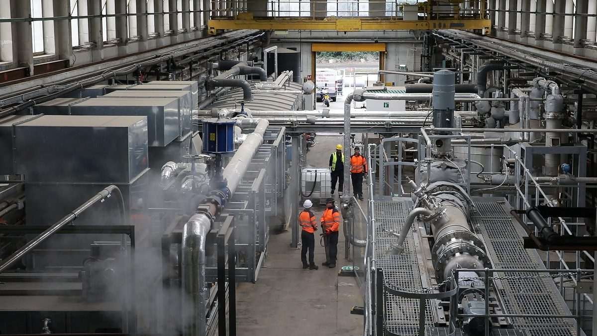 Workers inside Nova Pangaea’s Teesside demonstration plant, surrounded by industrial processing equipment, pipework and machinery