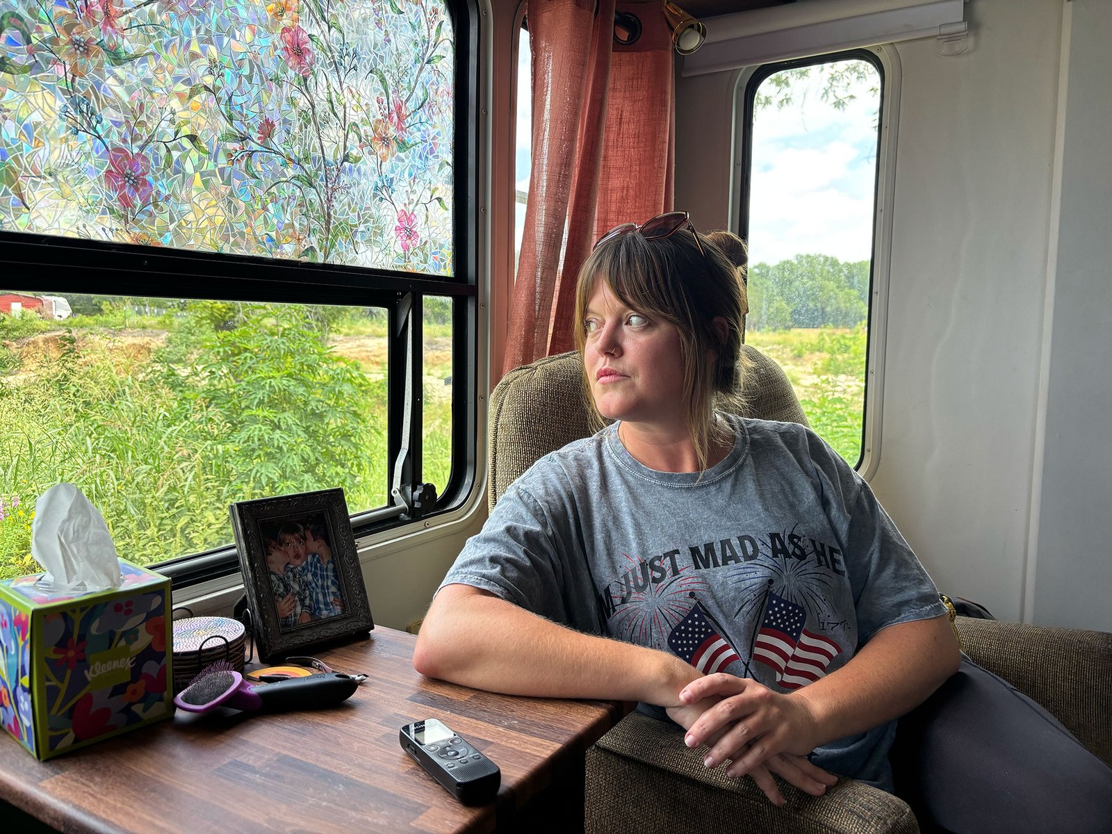 A woman sits in a mobile home looking out a window