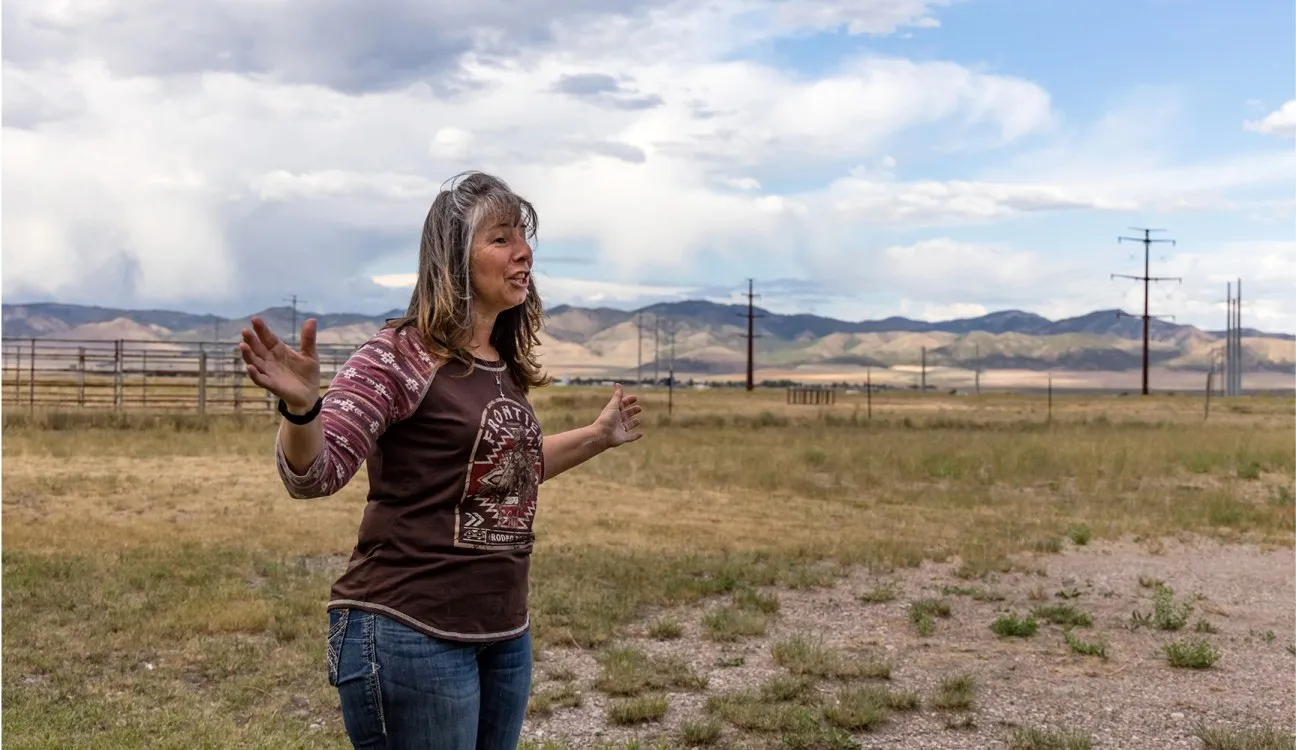 A woman stands in front of power lines