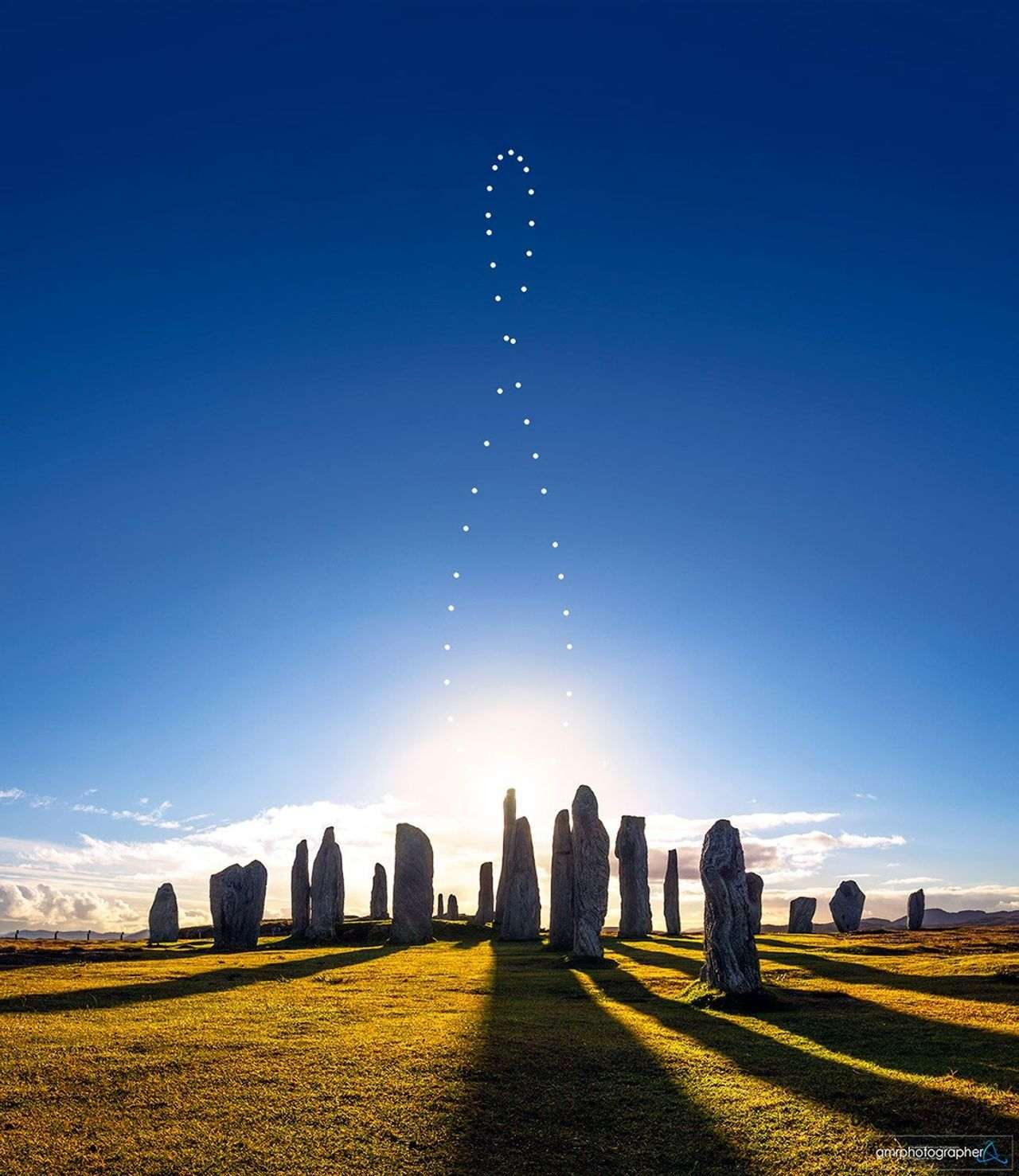 Multiple images of the Sun trace out an analemma curve in the daytime sky above the Callanish stones.