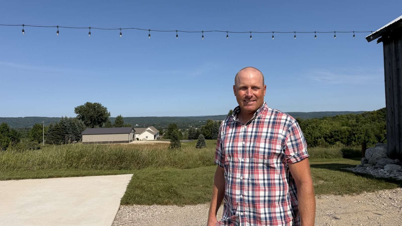A man stands in front of an agricultural field on a sunny, clear day.
