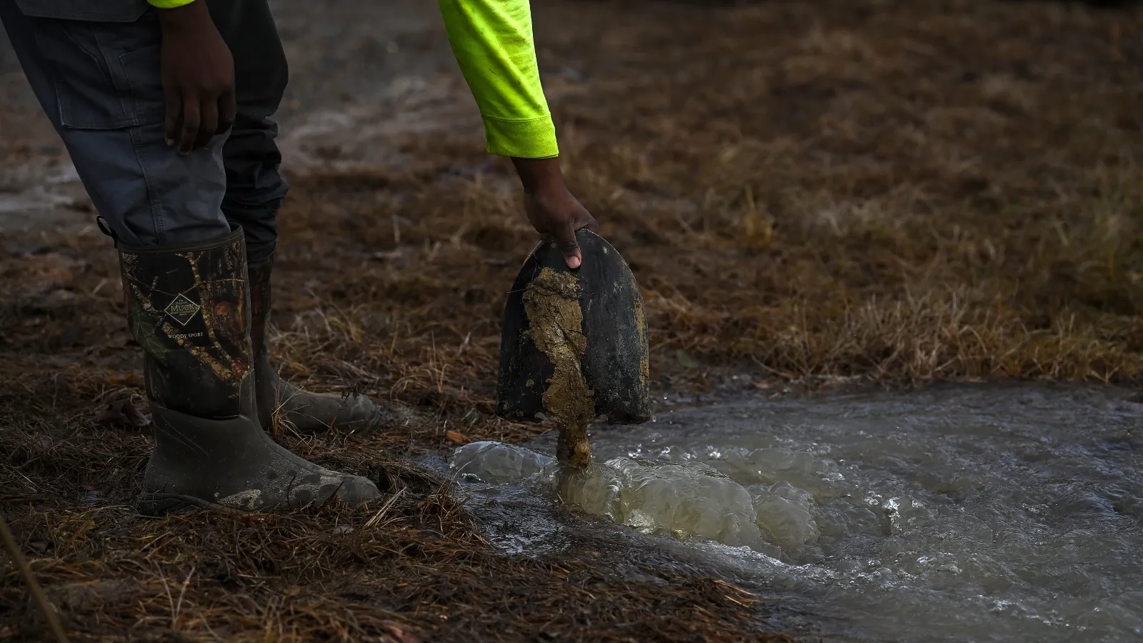 A man holds a shovel in a pool of water