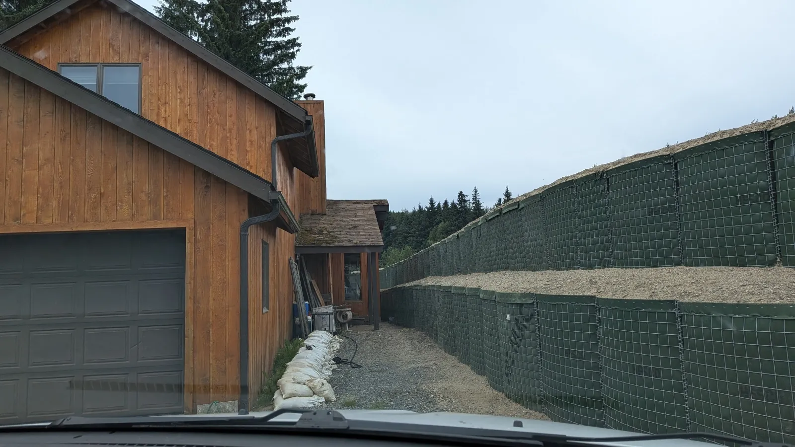 A green flood wall runs close to the side of a house