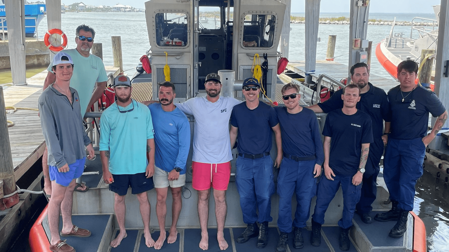 A group of people on a boat, several of them are wearing shirts with text reading "U.S. Coast Guard"