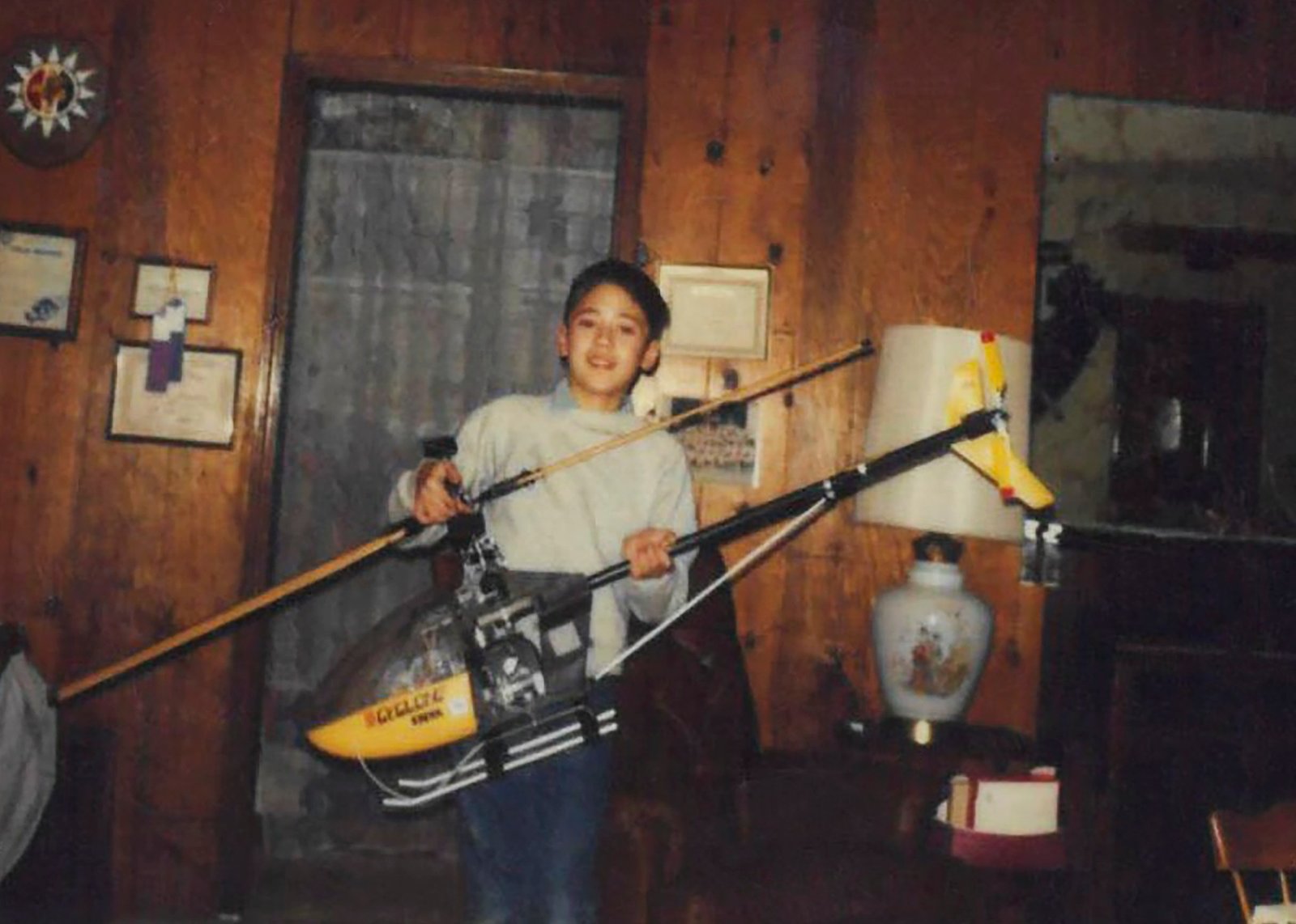 A boy holds a large radio-controlled black-and-yellow helicopter.