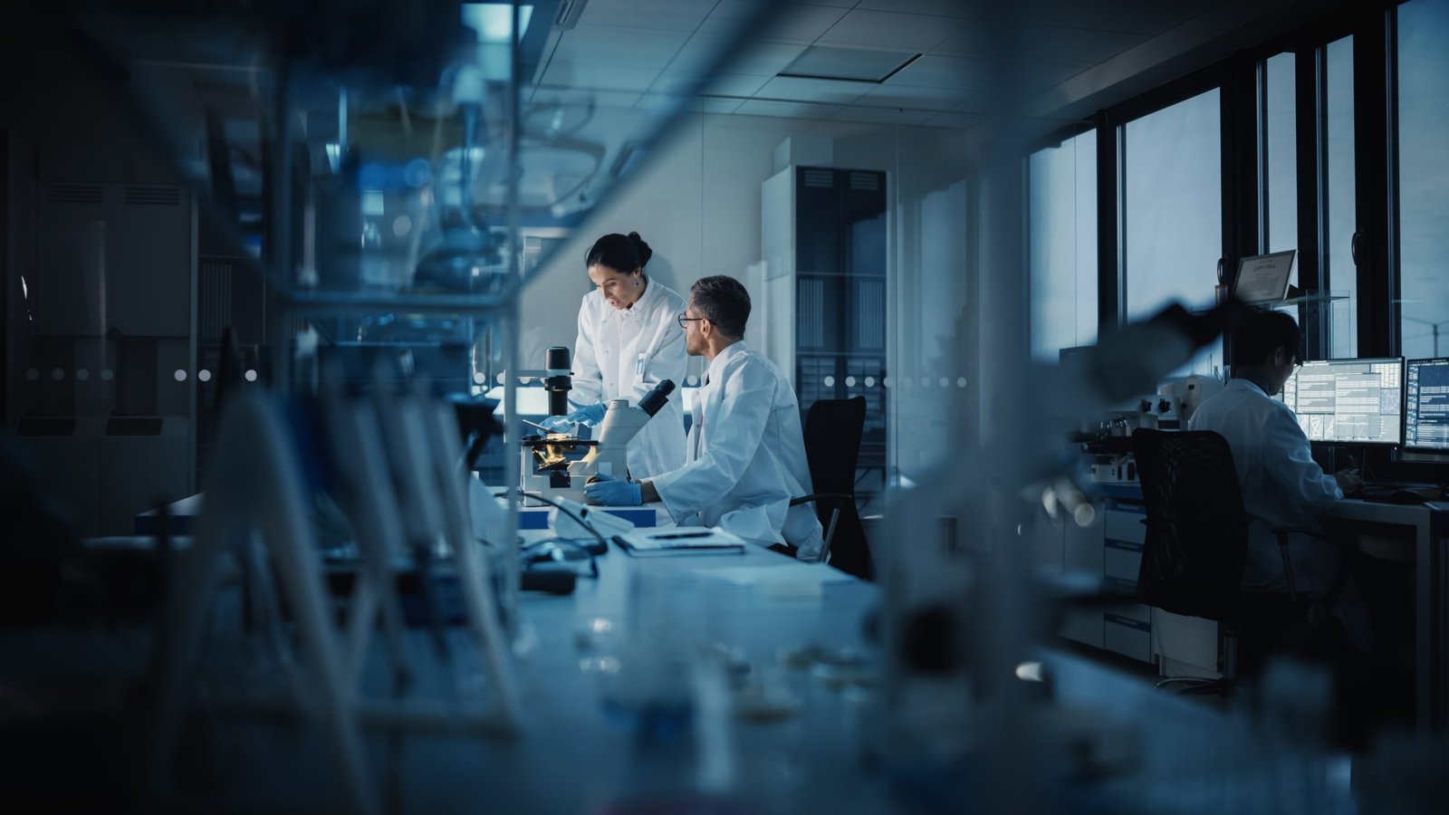 Scientists working with microscopes and computer equipment in a laboratory