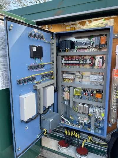 Open control cabinet containing electrical and monitoring equipment for a wastewater pumping system