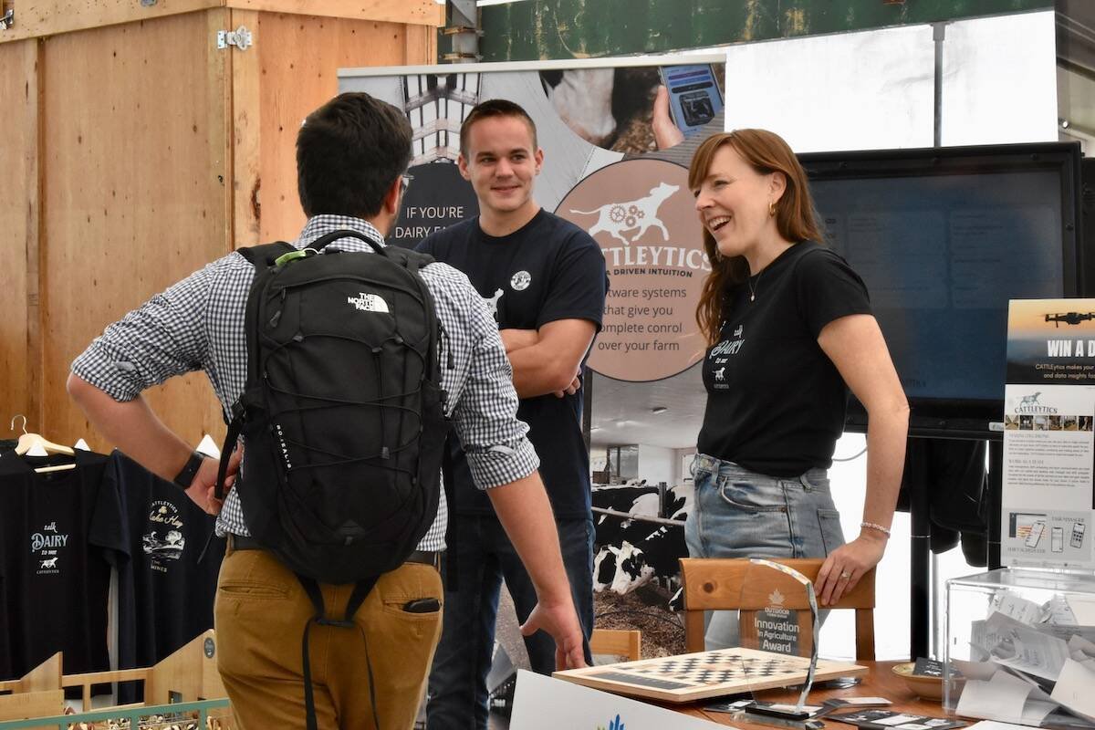 Two CATTLEytics staff talk with a visitor at the company's booth, an Innovation in Agriculture Award on the table.  Photo: Canada's Outdoor Farm Show

