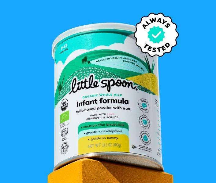 A canister of Little Spoon organic whole milk infant formula is displayed on a yellow block, with an “Always Tested” badge on a solid blue background.
