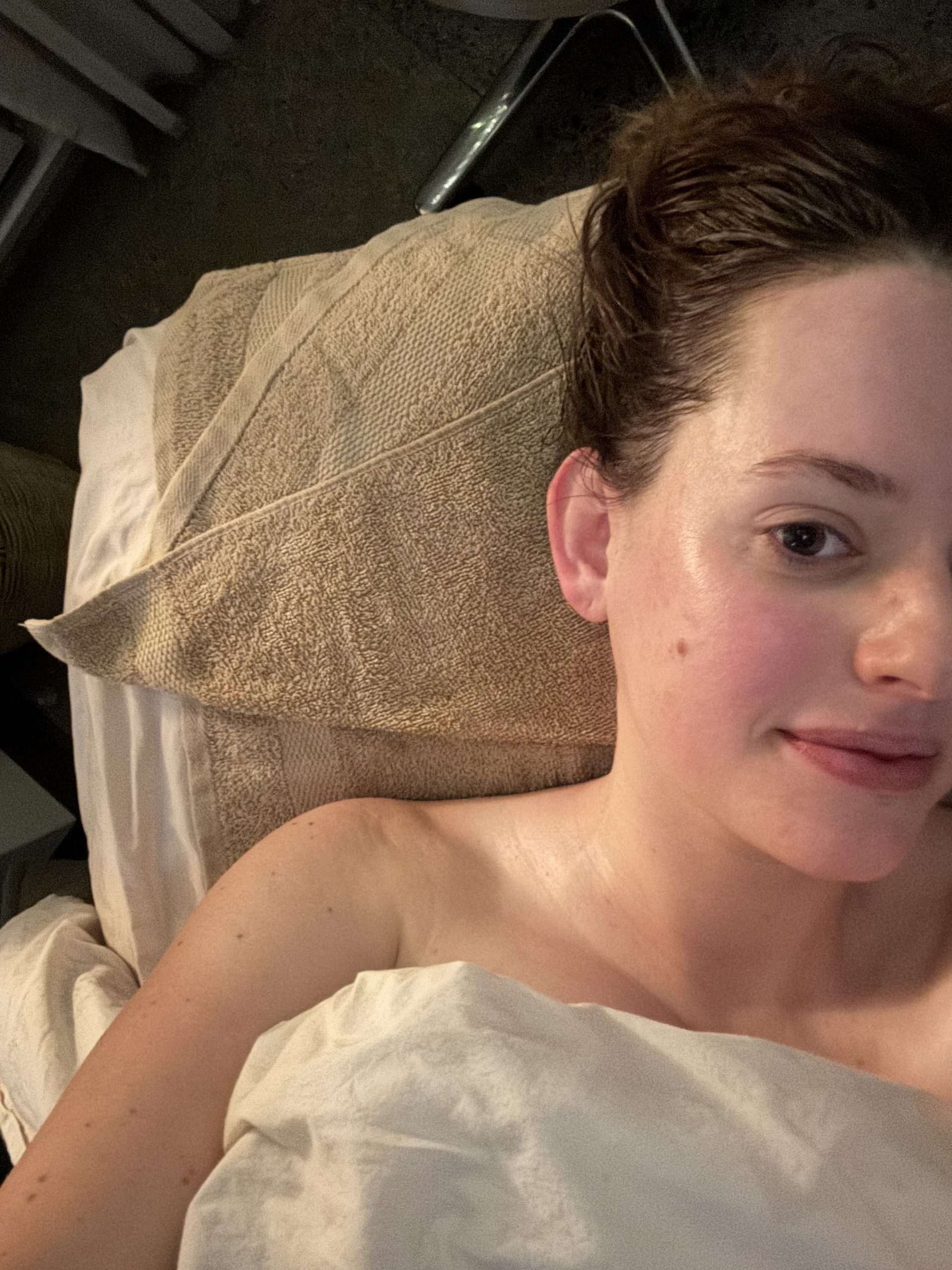 A woman lying on a spa treatment table with a towel tucked under her head.