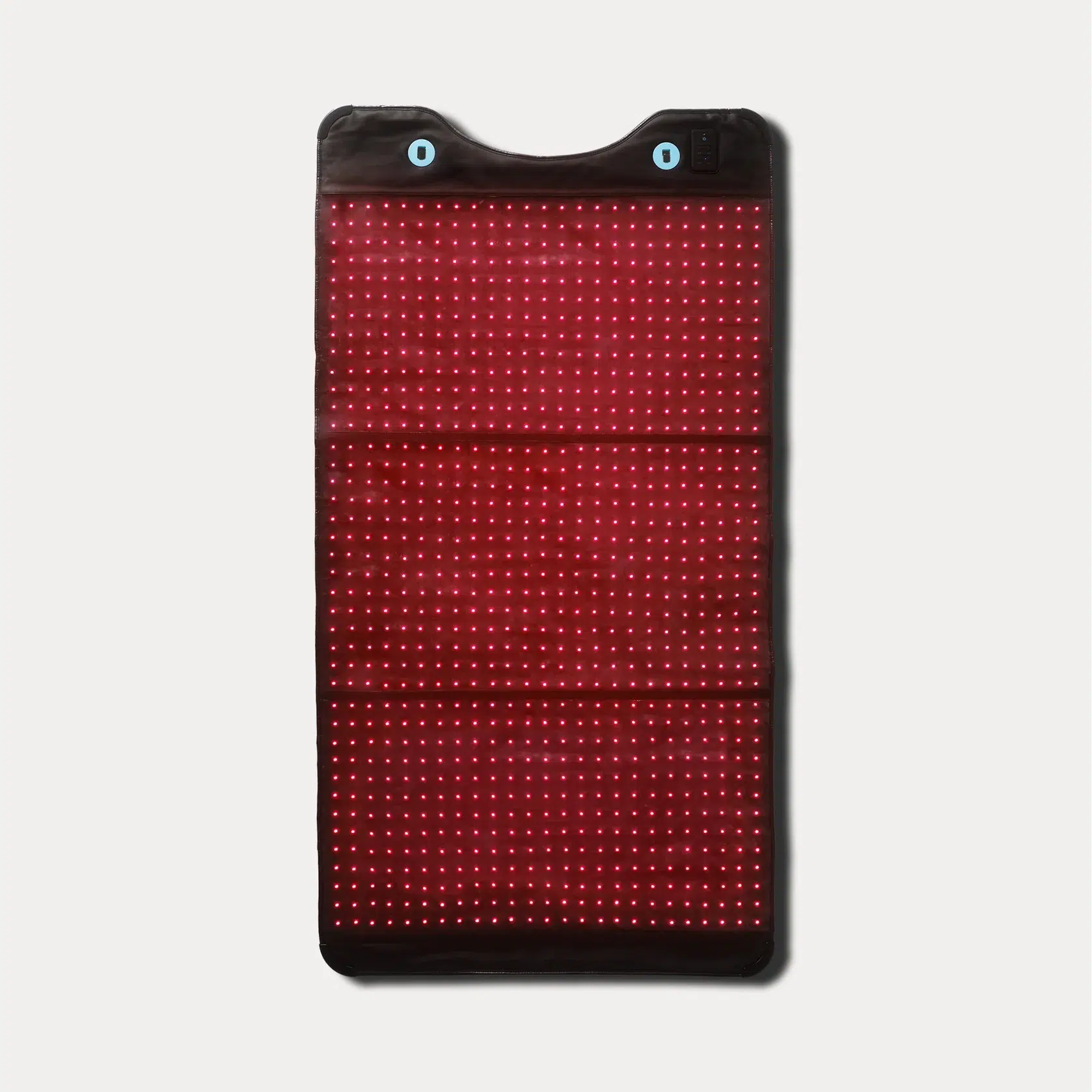 A rectangular red light therapy pad with evenly spaced illuminated LEDs, a black border, and two blue buttons at the top, displayed on a white background.