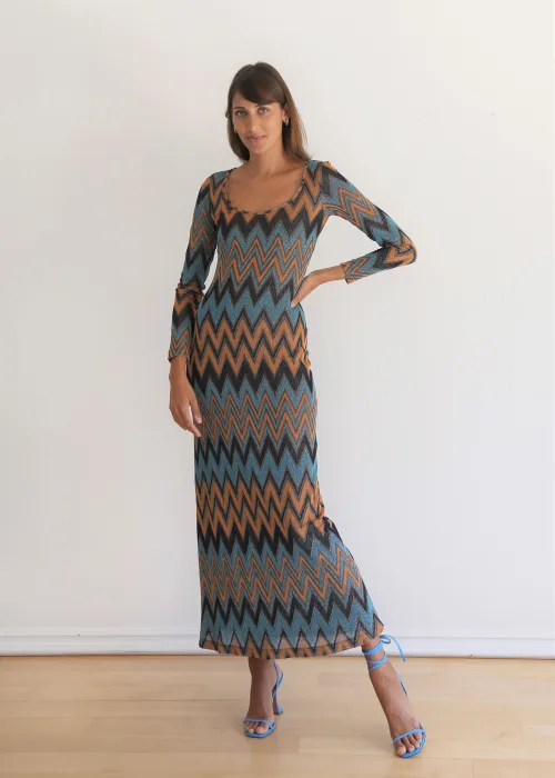 A woman wearing a long-sleeved, chevron-patterned maxi dress and light blue strappy heels.