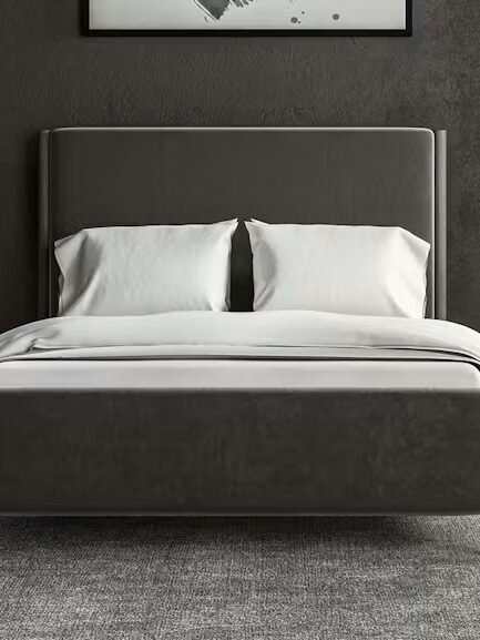 A modern bedroom with a dark gray bed, white bedding, two bedside tables with gold lamps, and floor-to-ceiling curtains.