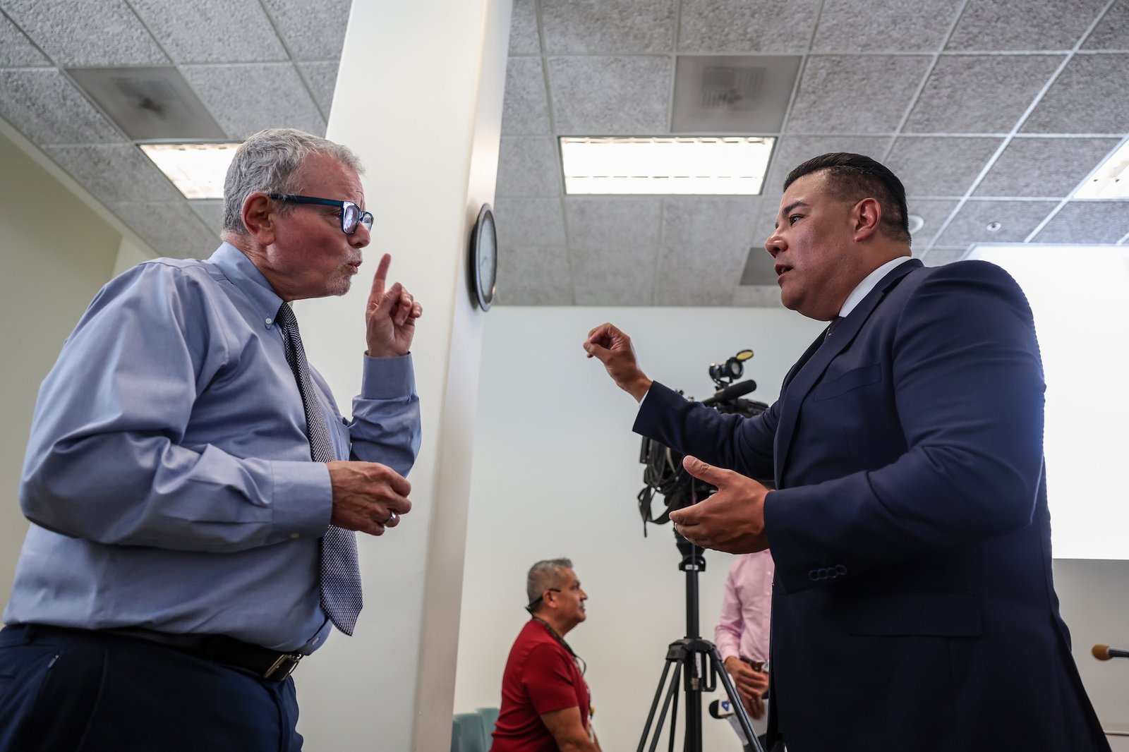 Two men have a heated conversation in a conference room