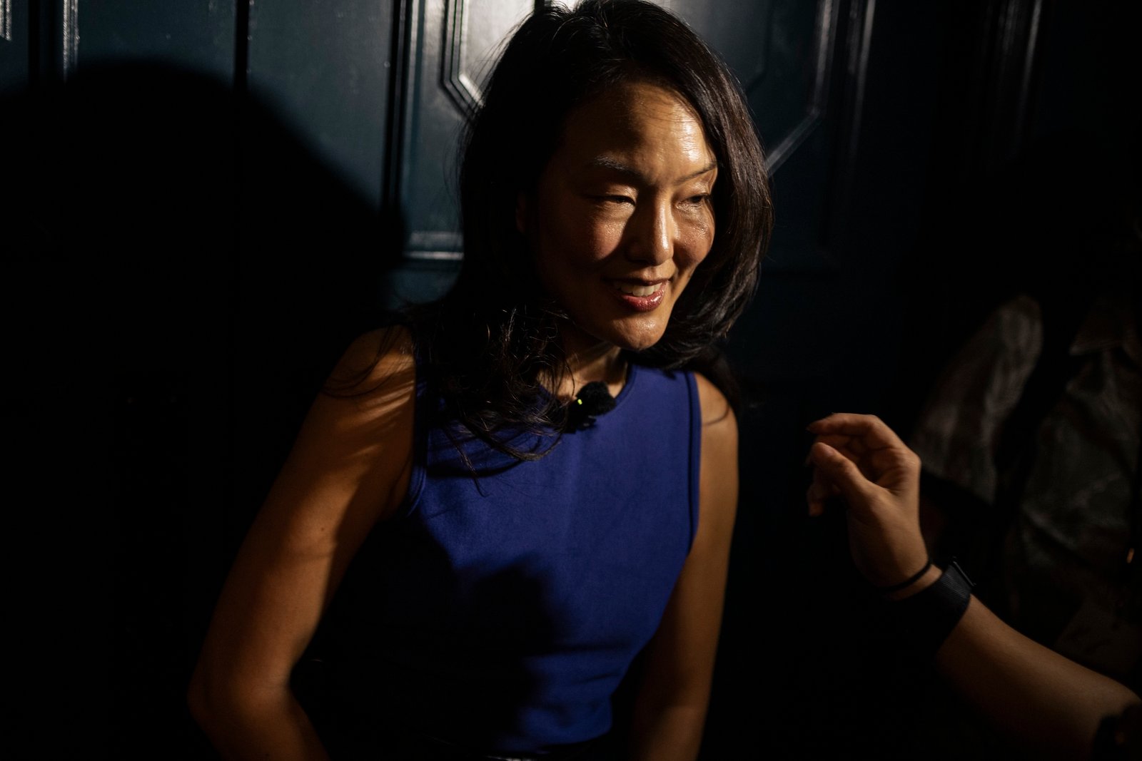 A woman smiles standing near a door