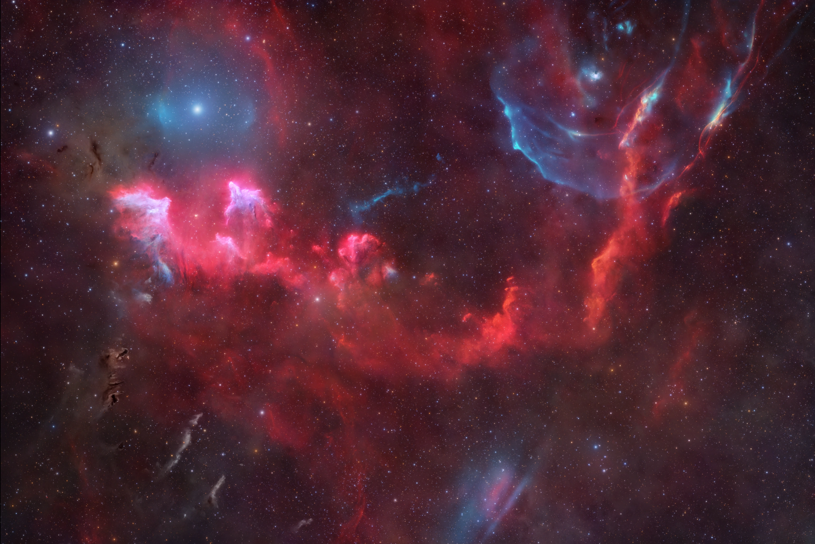 The sky is speckled with stars. Bright tufts of emission nebulae trace across the image's equator. Arcs and smudges of ionized oxygen emission also included.