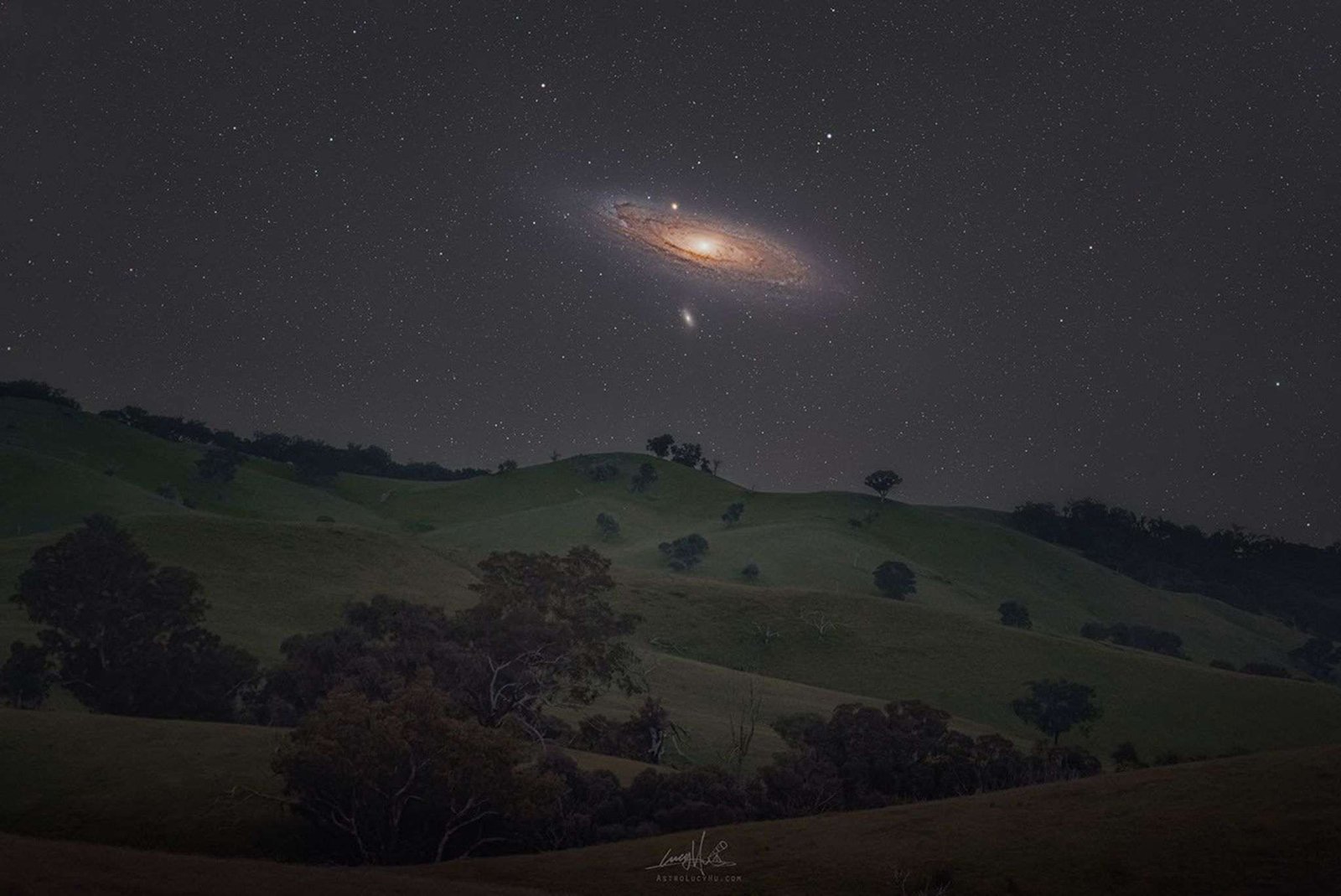 The Andromeda galaxy above rolling hills.