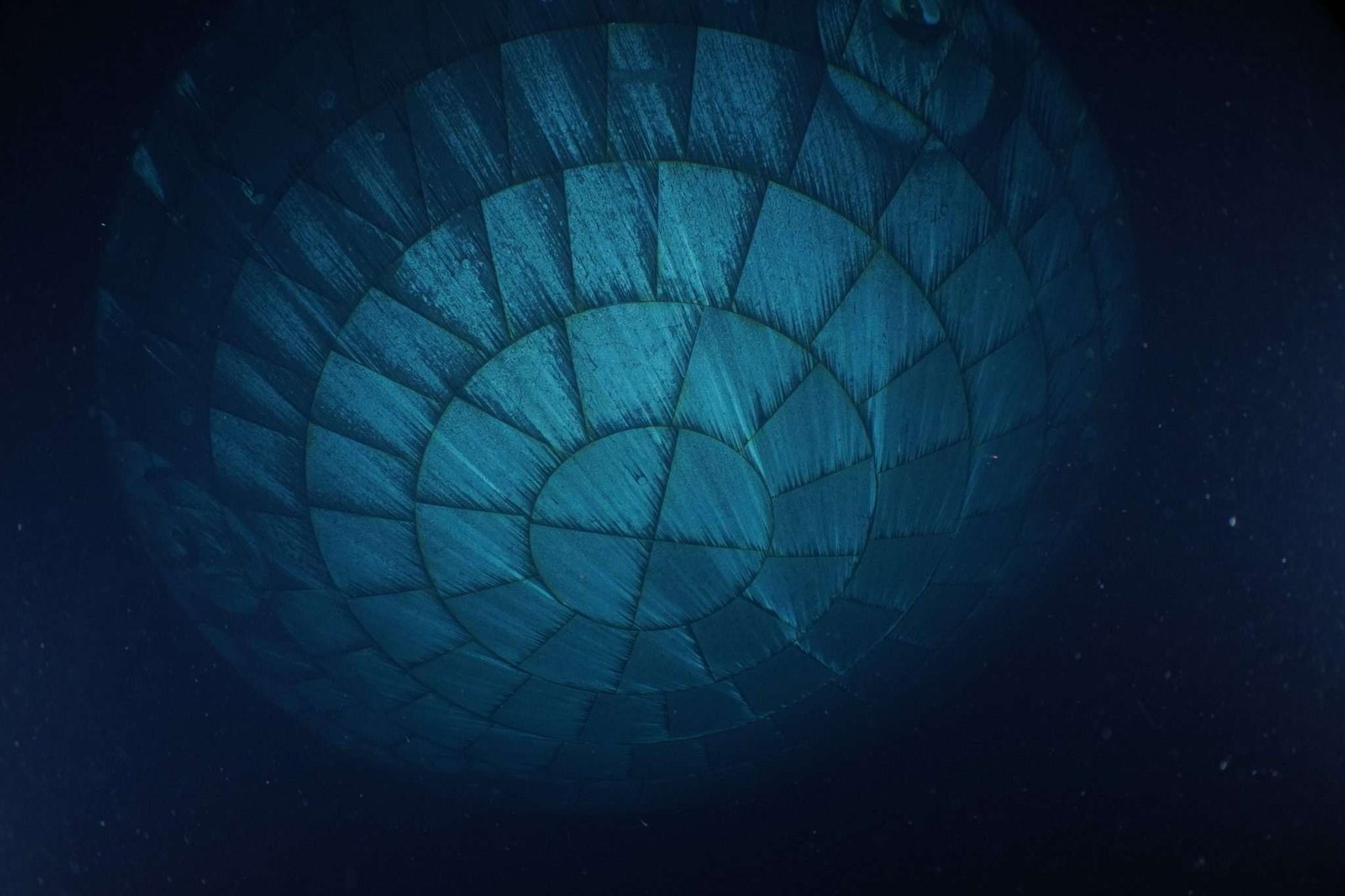 The Orion spacecraft's heat shield dominates this underwater photo. Due to the water, the heat shield appears to be teal-colored.