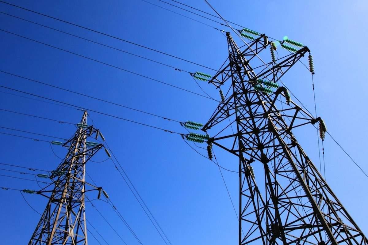 High-voltage electricity pylons and overhead transmission lines against a blue sky
