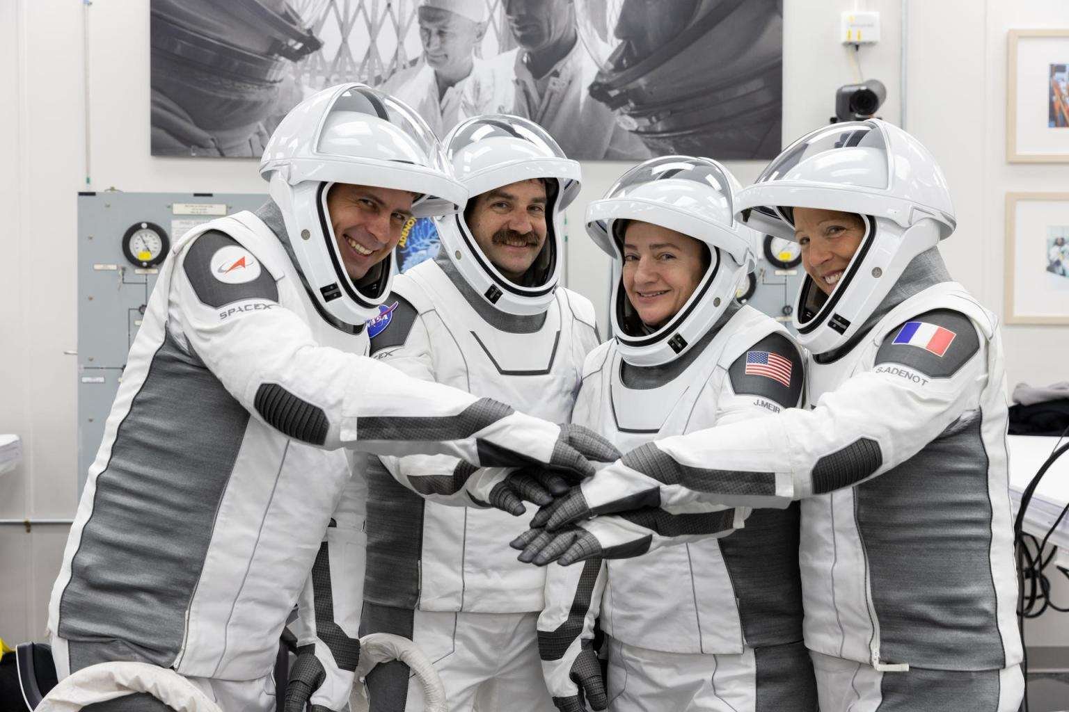 NASA’s SpaceX Crew-12 astronauts stand side by side in their spacesuits with face shields raised. They extend their arms forward, stacking their hands together in a team huddle while smiling. Pictured at the Neil A. Armstrong Operations and Checkout Building at Kennedy Space Center ahead of their Feb. 13, 2026 launch to the International Space Station, from left to right: Roscosmos cosmonaut Andrey Fedyaev, NASA astronauts Jack Hathaway and Jessica Meir, and ESA astronaut Sophie Adenot.