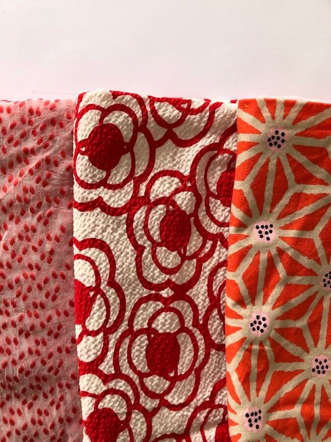 Three fabric swatches in a variety of red patterns.