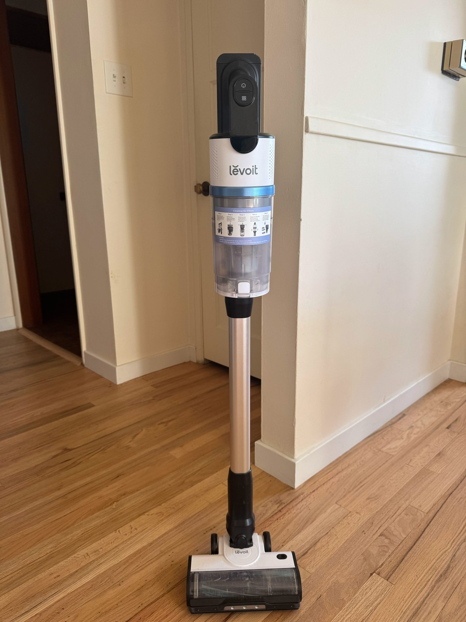 Levoit stick vacuum cleaner standing upright on a hardwood floor.