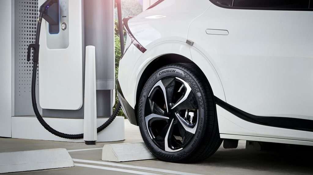A white electric vehicle charges. It has a black Kumho tire.