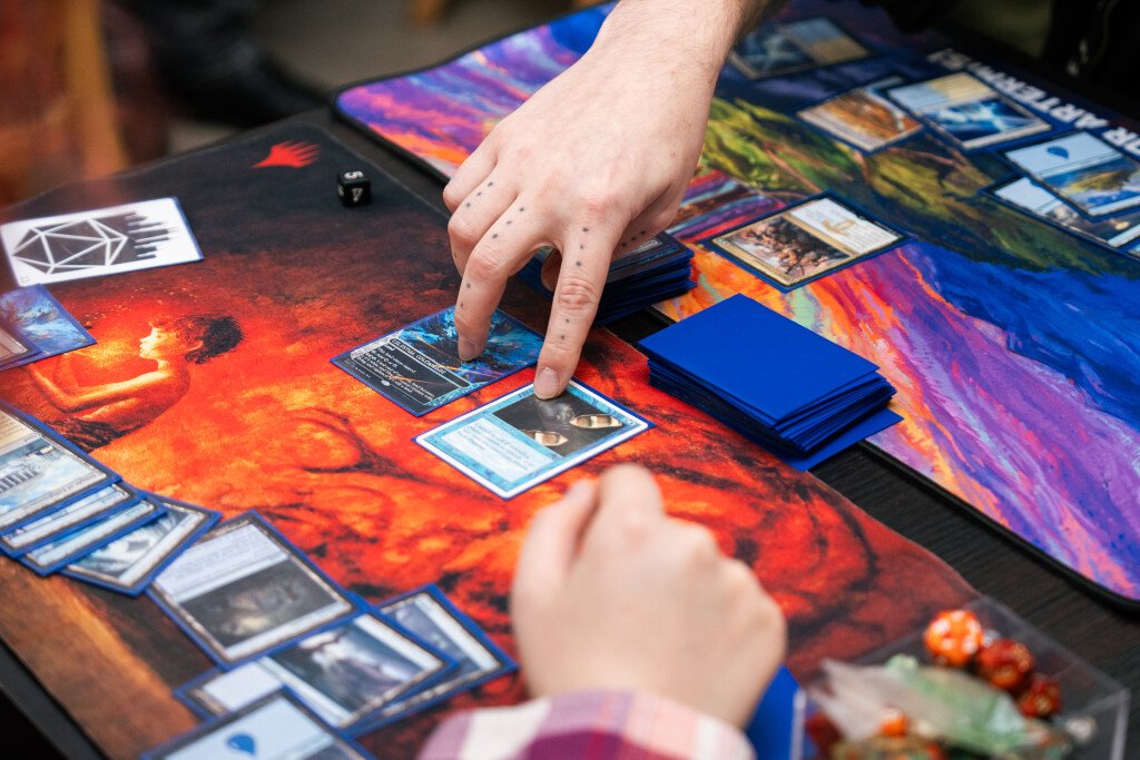 Hands point at Magic: The Gathering cards