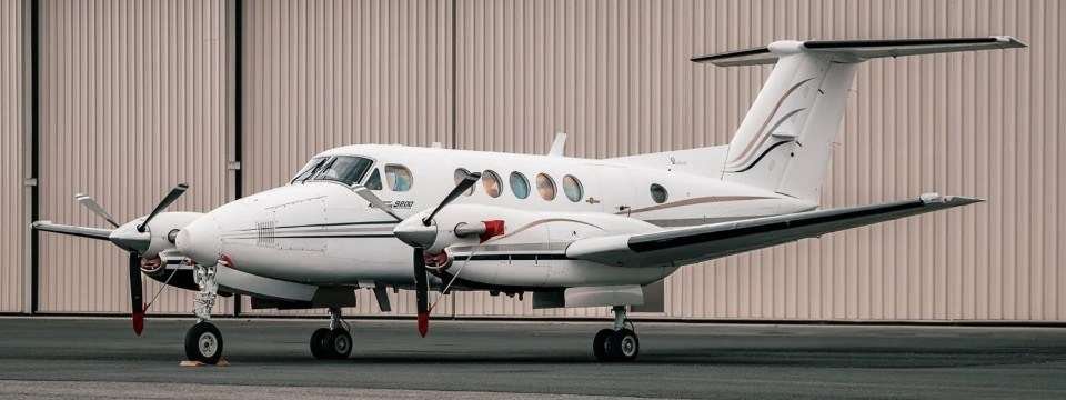A two engine aircraft sitting in front of a hangar.