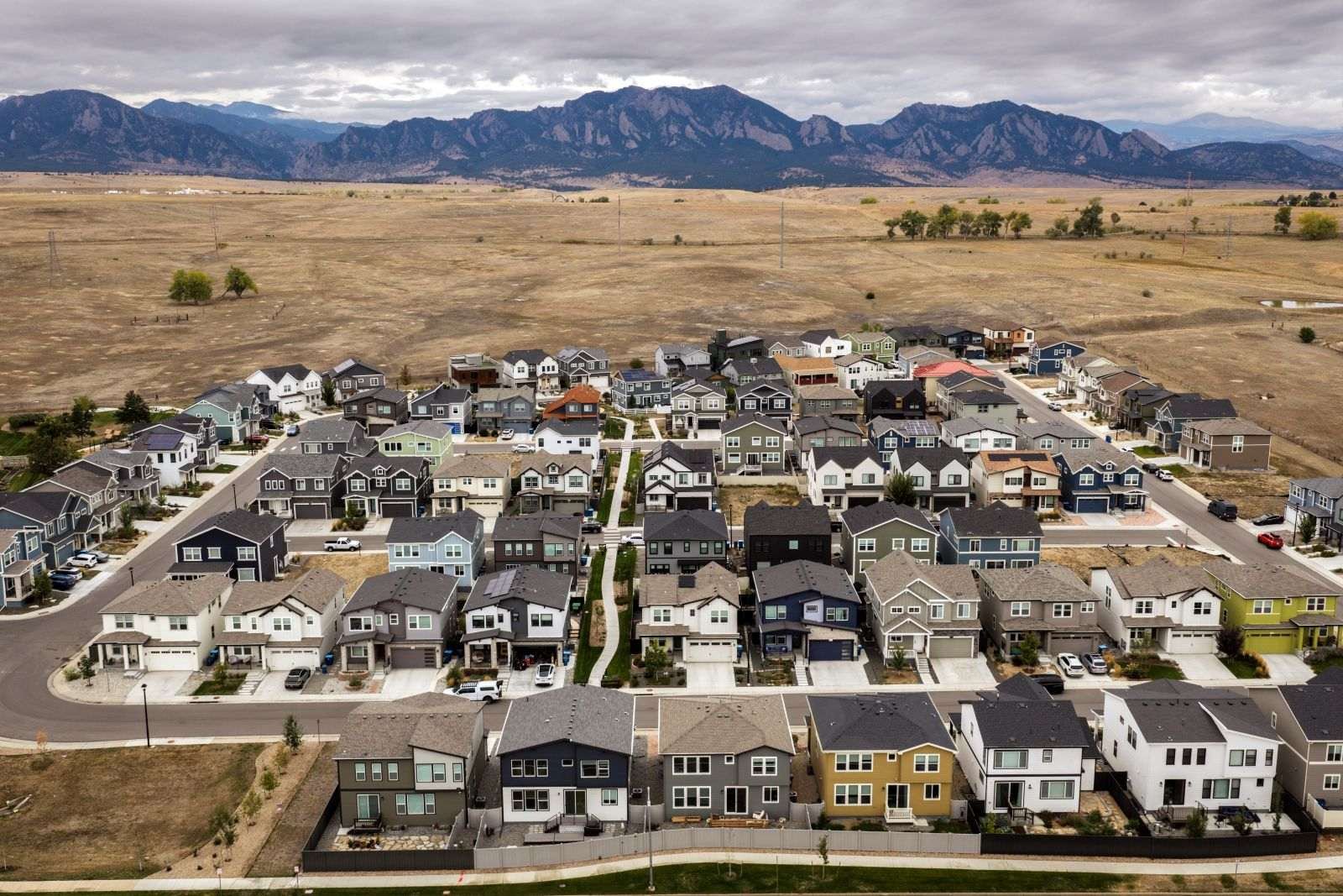 A housing development stands before the Rocky mountains