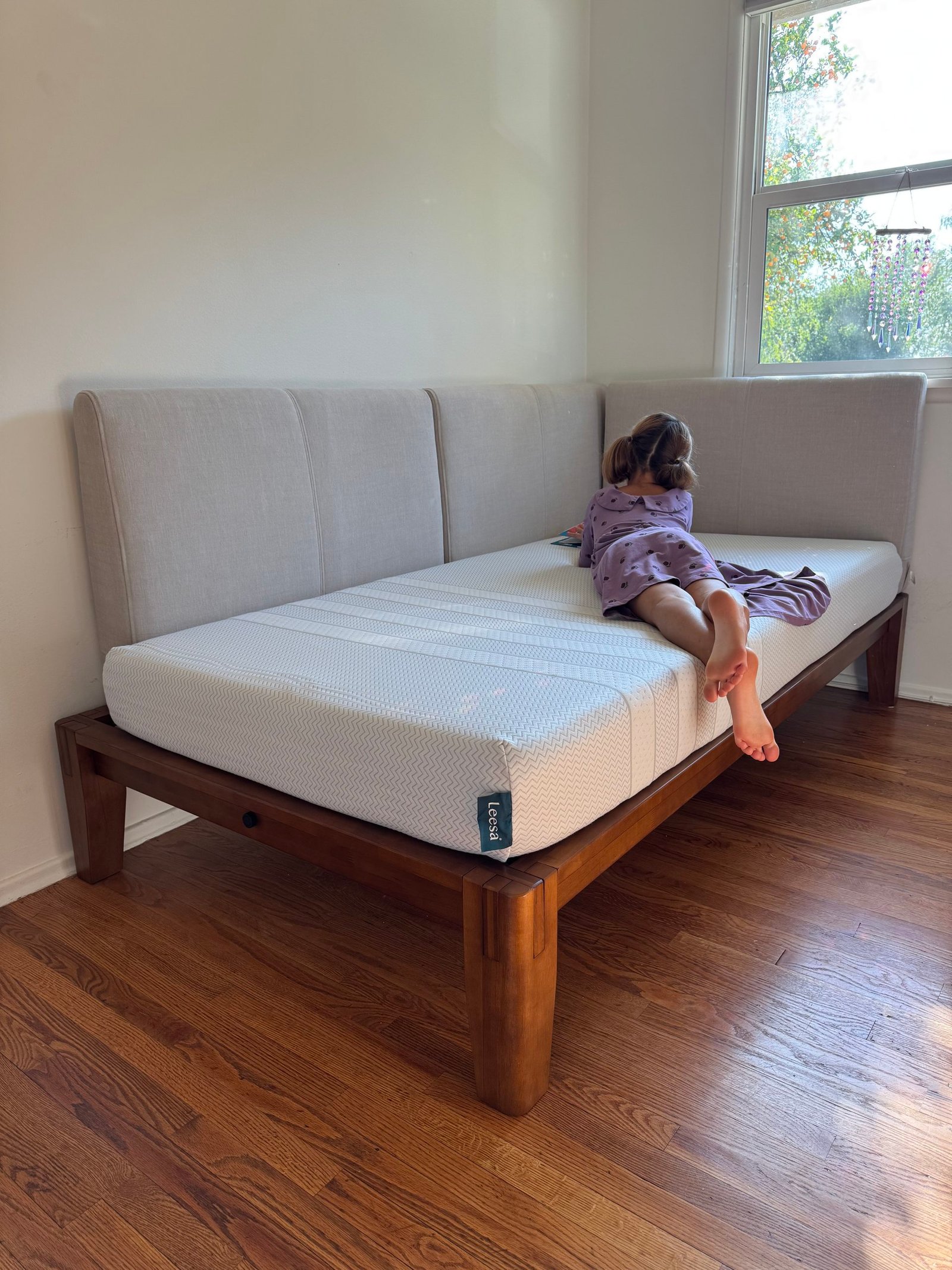 A child lying on their stomach on a Leesa mattress set in a corner bed frame.
