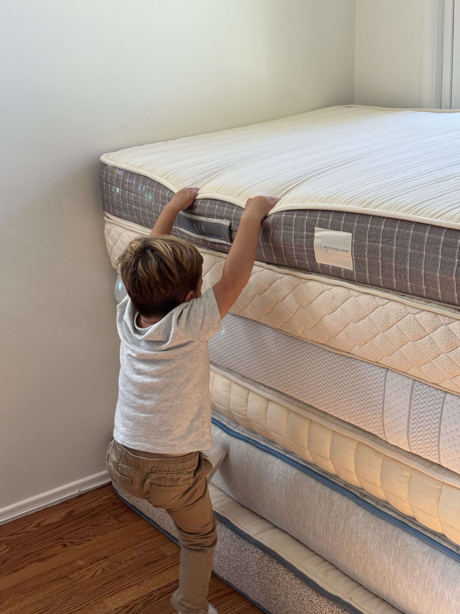 A young child climbing a stack of five mattresses.