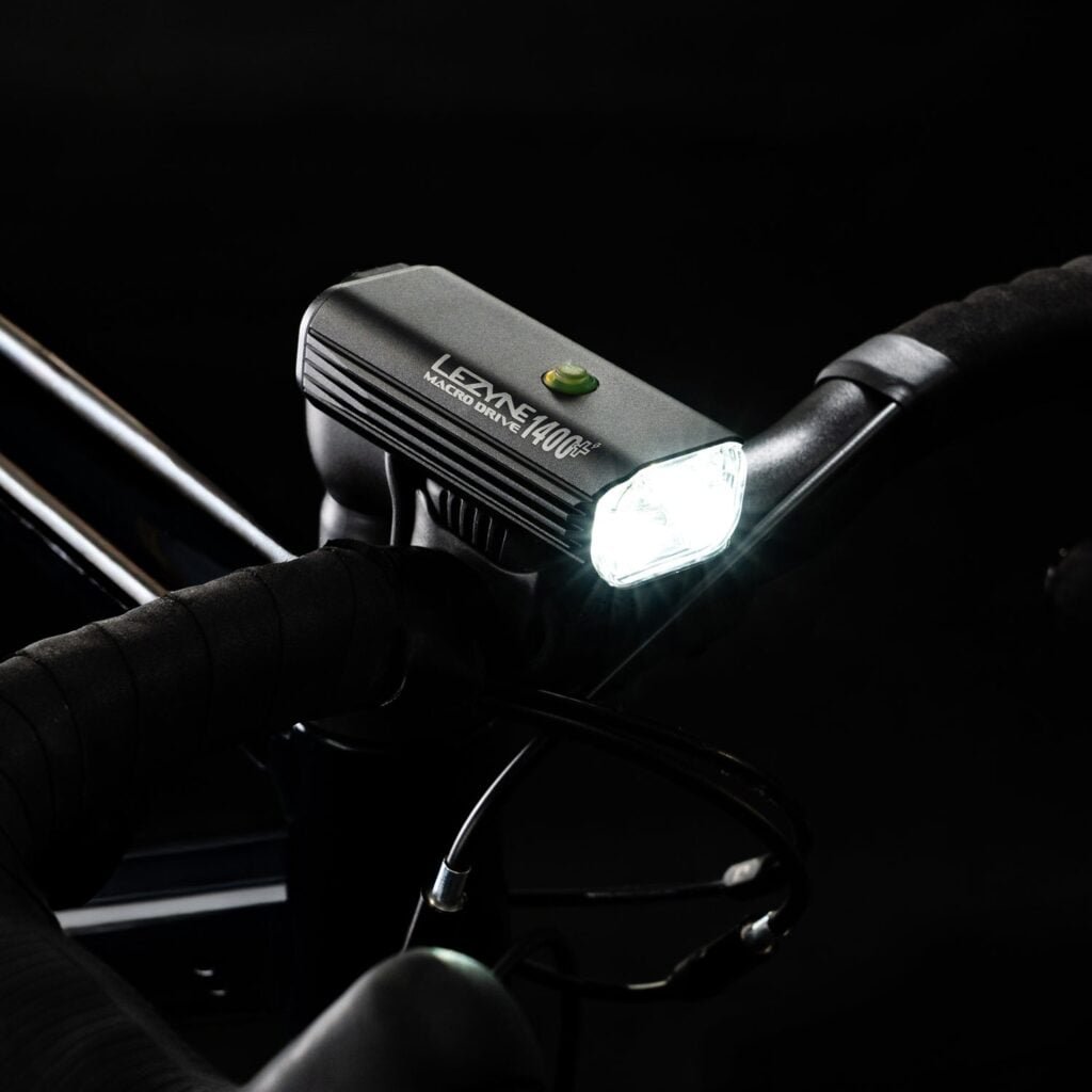 Lezyne Macro Drive 1400+ front bike light lit up on a handlebar at night