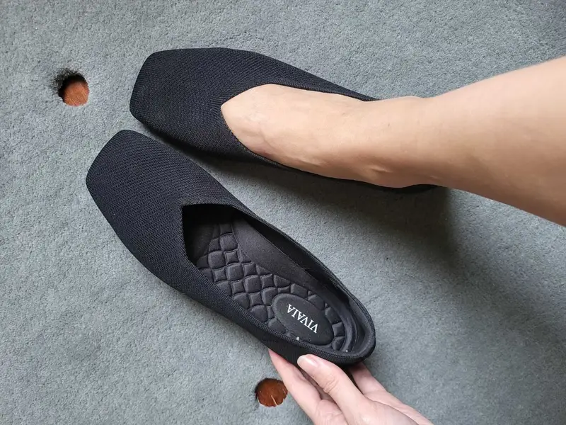 A pair of black, square-toe knit flats with VIVAIA branding on the cushioned insoles.