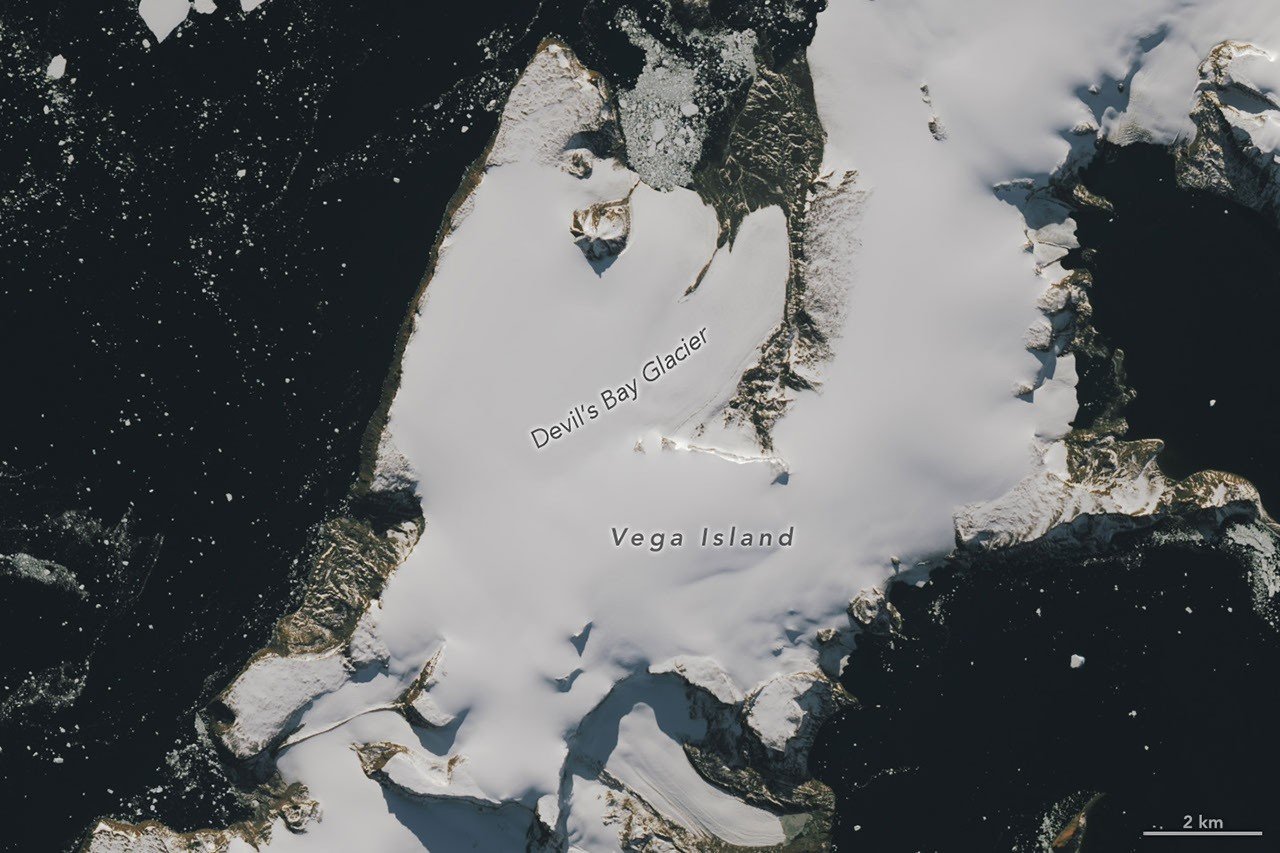 Part of an ice-covered Antarctic island has the appearance of a grinning skull in profile, with a rock outcrop as an eye socket and lateral moraine as a mouth.